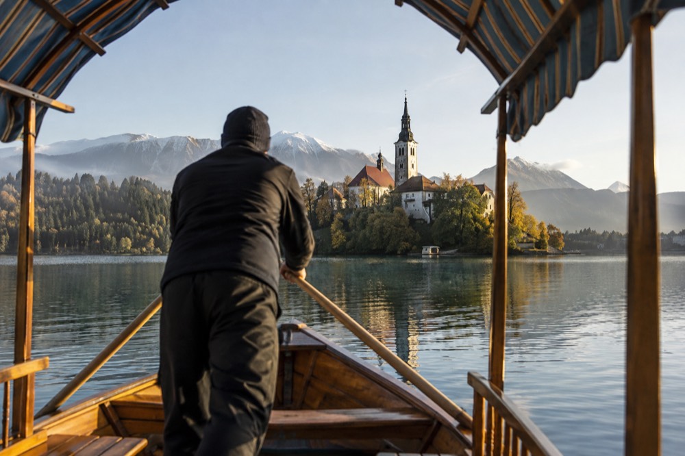 Wooden pletna boat approaching the island church on Lake Bled