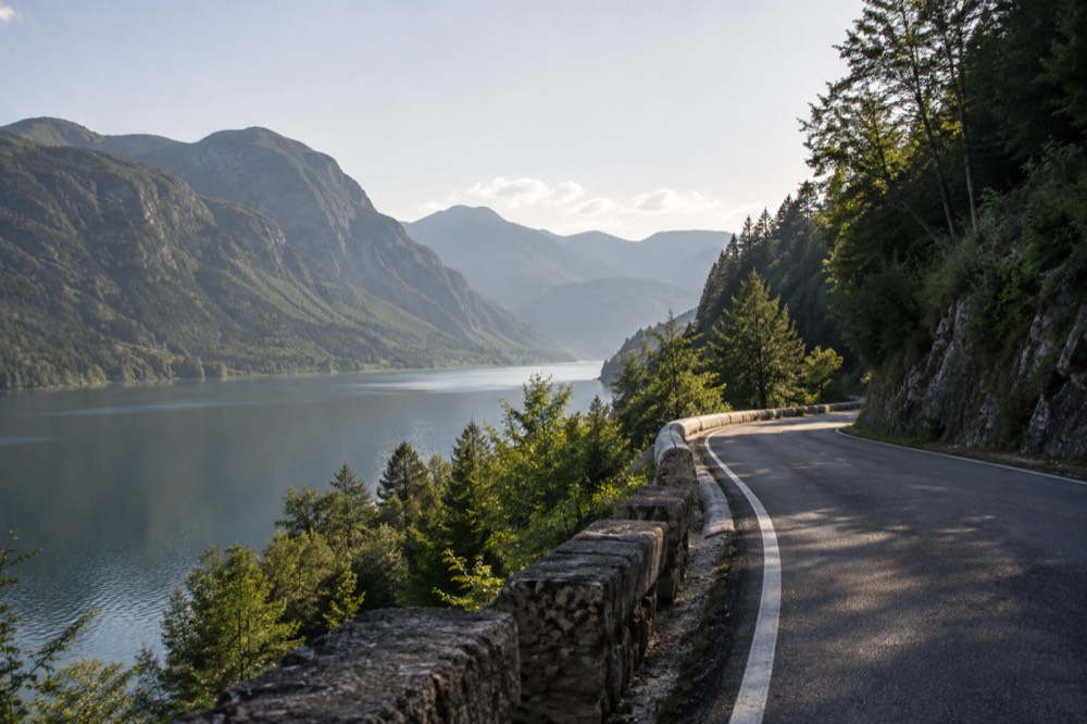 A winding valley road through forest with steep green mountainsides on both sides