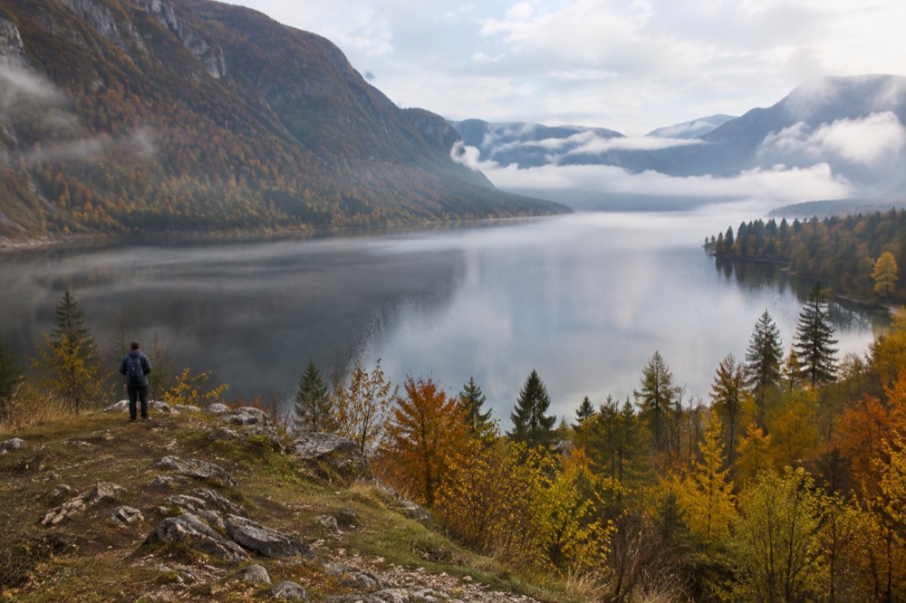 Autumn colours on hillsides above a lake with early morning mist on the water
