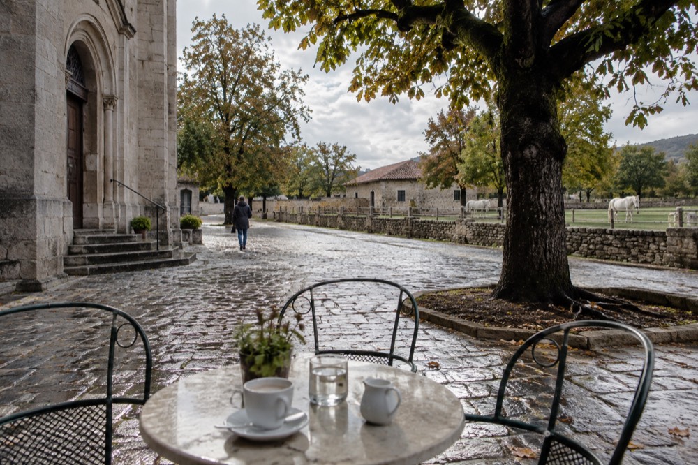An outdoor cafe table on a cobbled square beside a stone church facade