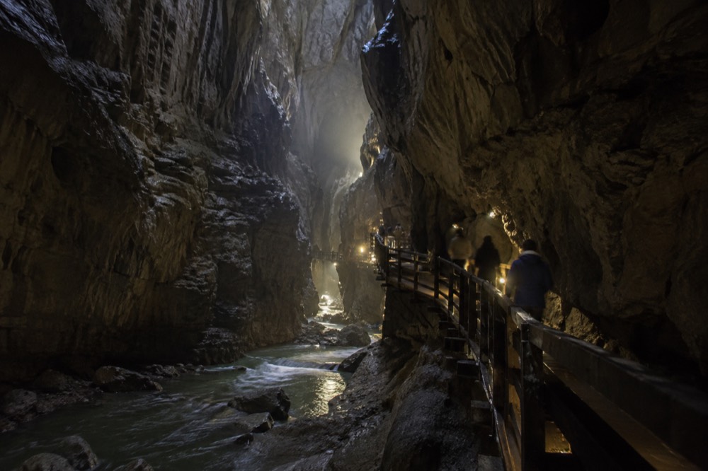 Wooden walkway inside a vast limestone cave canyon above a river