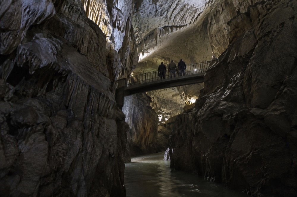 Underground river canyon inside a cave crossed by a narrow footbridge