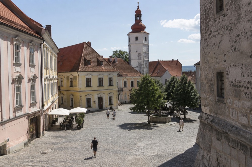 A cobbled square with pastel-coloured old buildings and a stone tower