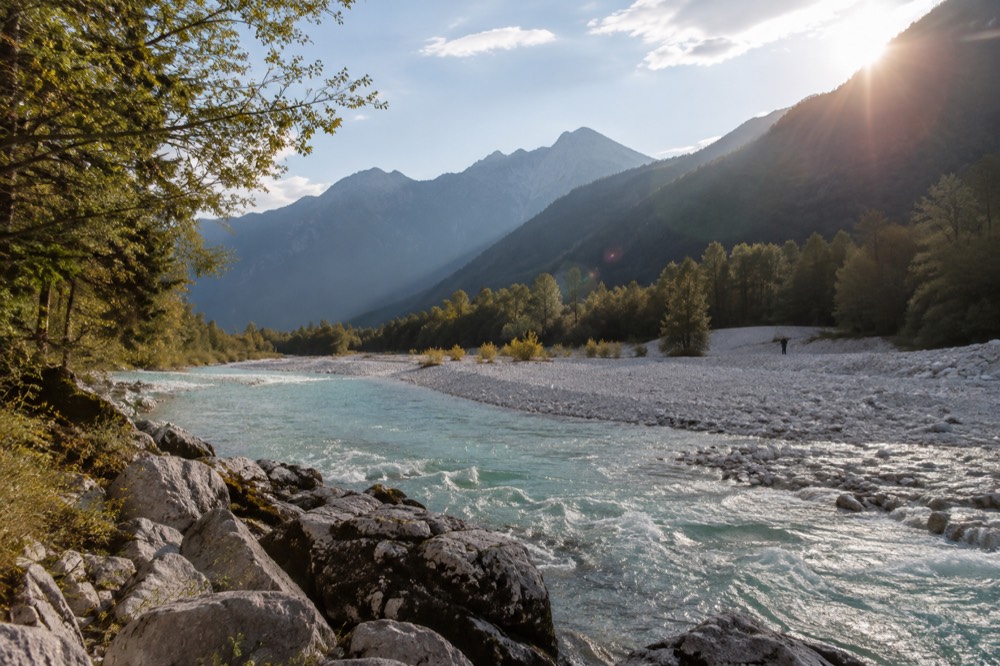 The turquoise Soča River winding through a wide gravel riverbed with mountains behind