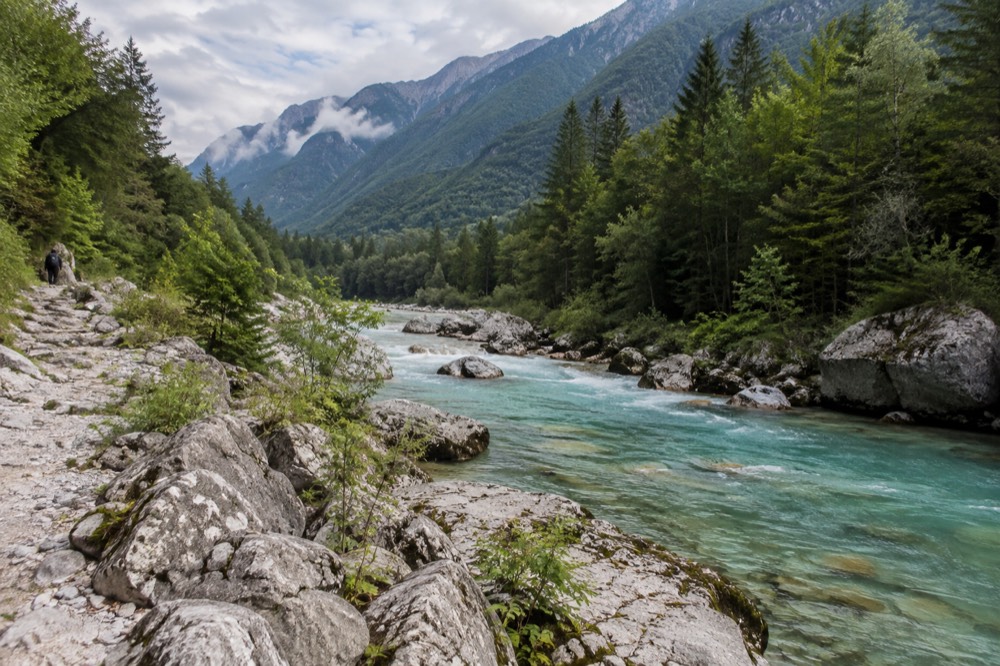 Turquoise river winding through a wide alpine valley with forested slopes