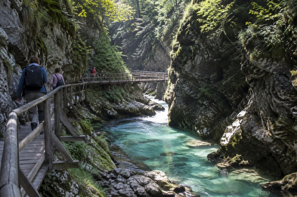 Wooden walkway running along a turquoise river between steep gorge walls