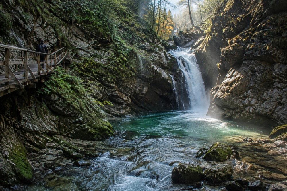 A waterfall dropping into a rocky pool at the end of a narrow gorge