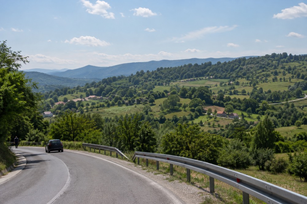Green countryside with rolling hills seen from a road near a border crossing