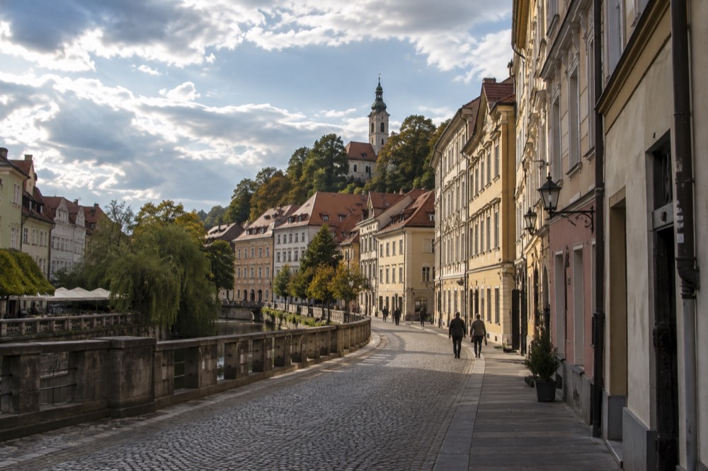 Cobbled street with old houses and a church tower on a hilltop old town