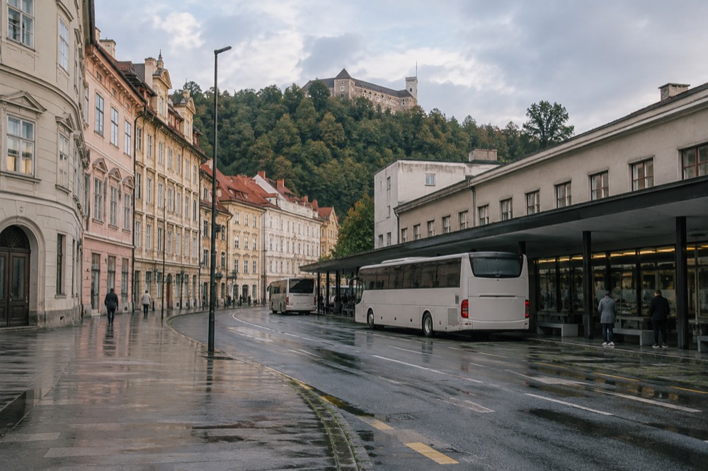A coach parked at an intercity terminal with a station building behind it
