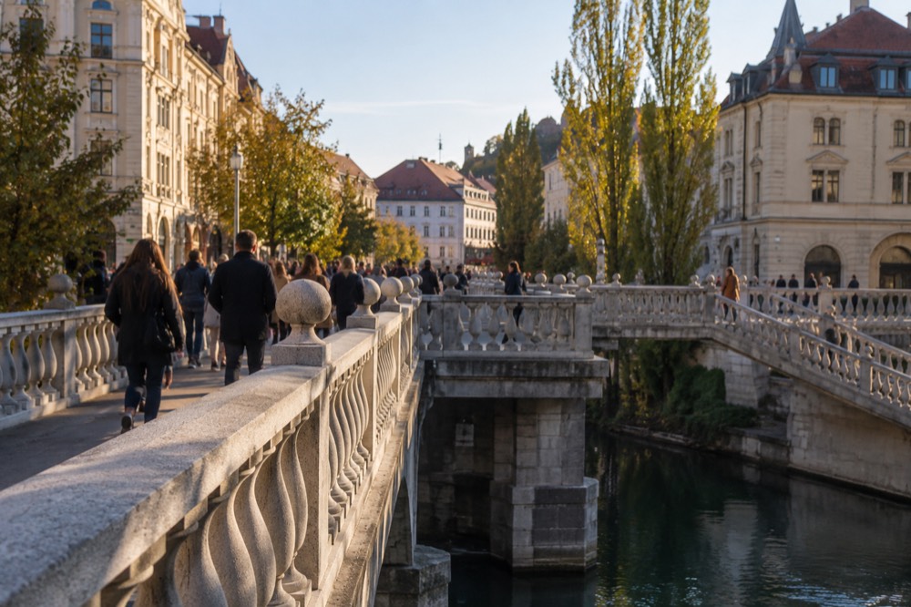 Pedestrians crossing the Triple Bridge over the Ljubljanica on a sunny afternoon