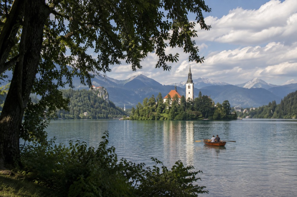 Bled Island and a rowing boat on calm water beneath a summer sky