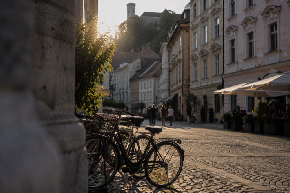 A small group of bicycles standing together on a cobbled square at the edge of the old town