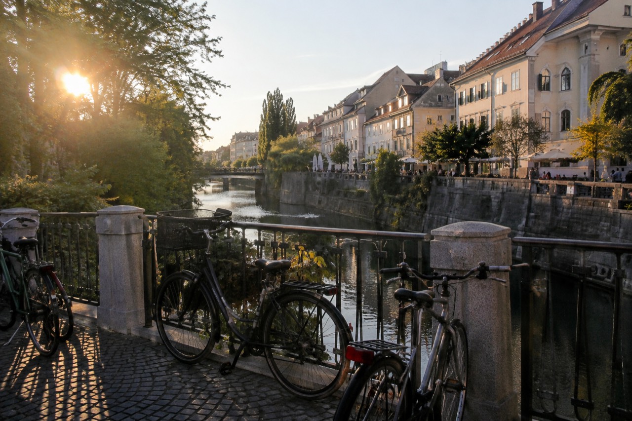 Bicycles parked beside the Ljubljanica river with the old city centre behind them