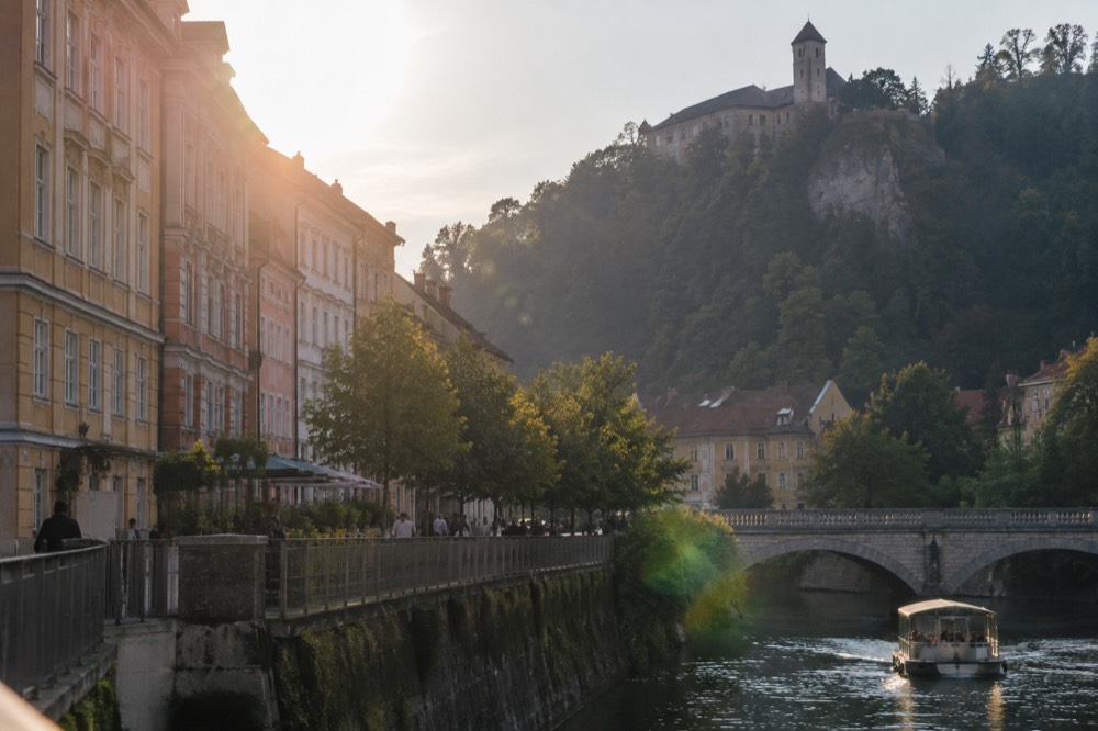 A boat on a lake beneath a castle on a cliff above green water