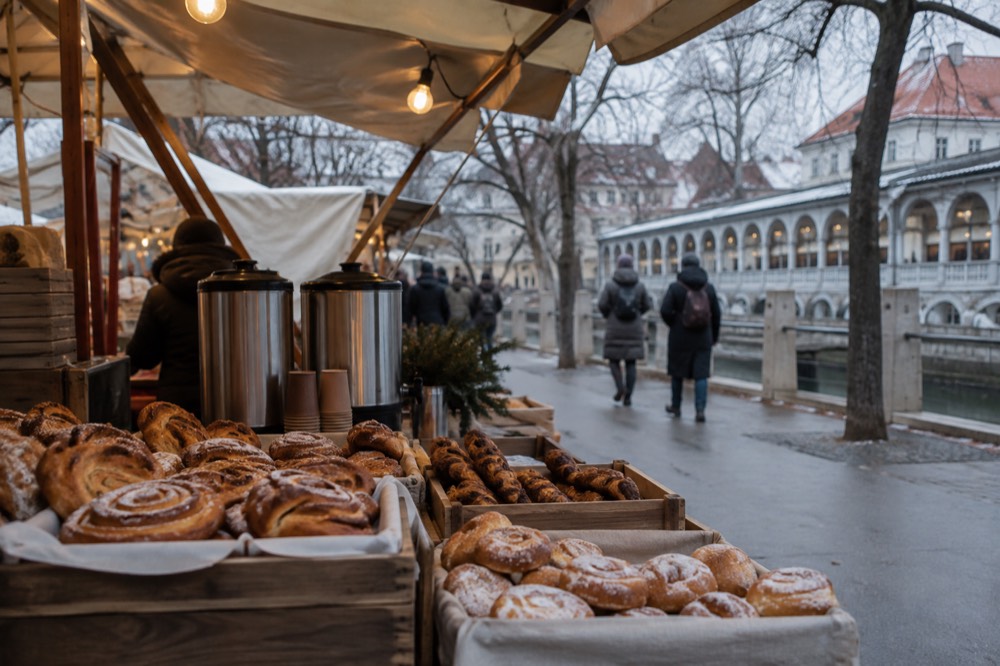 A close view of a market food stand with pastries and warm drinks under string lights