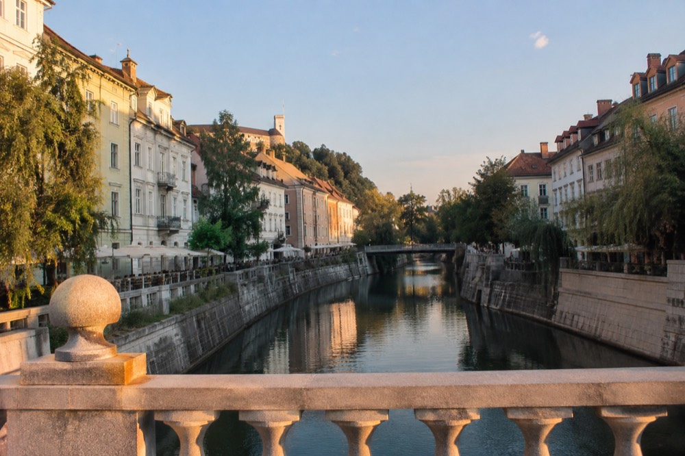 Pastel coloured Baroque buildings lining the Ljubljanica river in Ljubljana on a bright morning