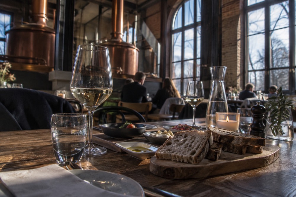 A table set with wine glasses, bread and small tasting plates in a rustic interior