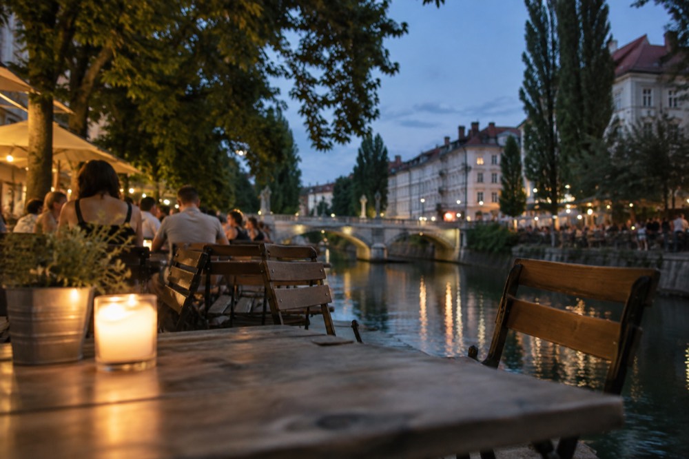 Crowds at evening café tables along the Ljubljanica riverbank in summer
