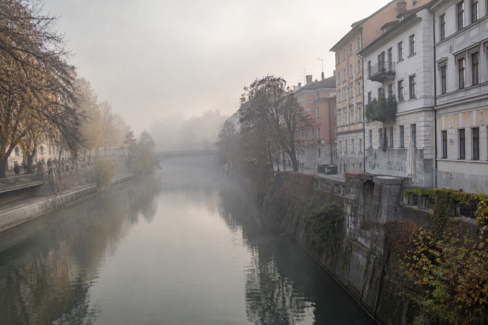 Fog over the Ljubljanica river and Ljubljana's riverside buildings on an autumn morning
