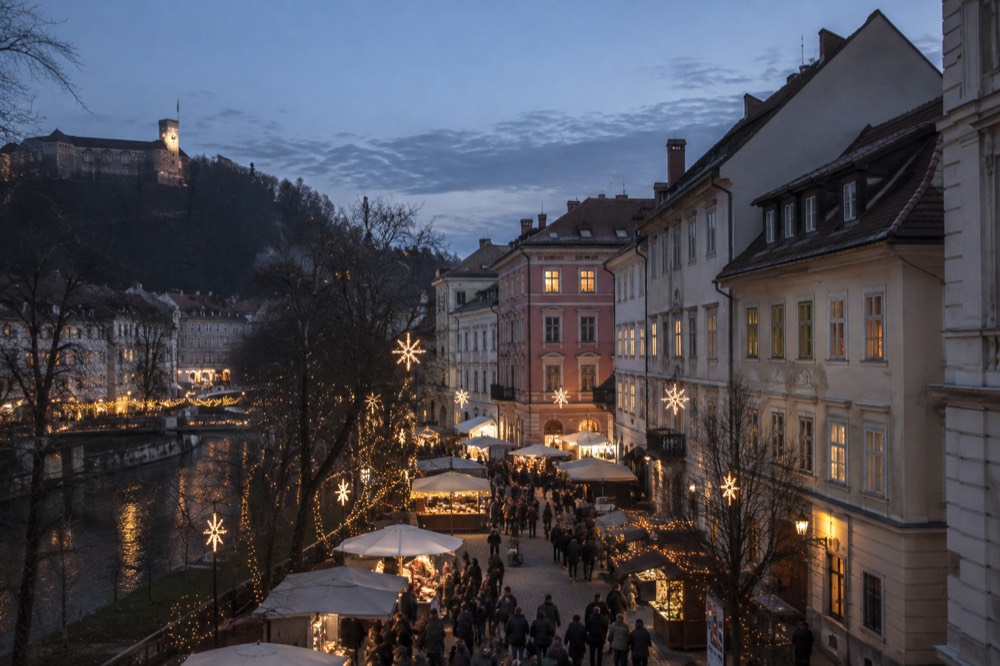 Festive lights above a Ljubljana square with market stalls in the evening