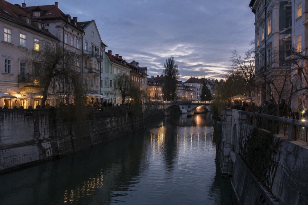 Pastel buildings and a stone bridge along the Ljubljanica river in Ljubljana's pedestrianised old centre
