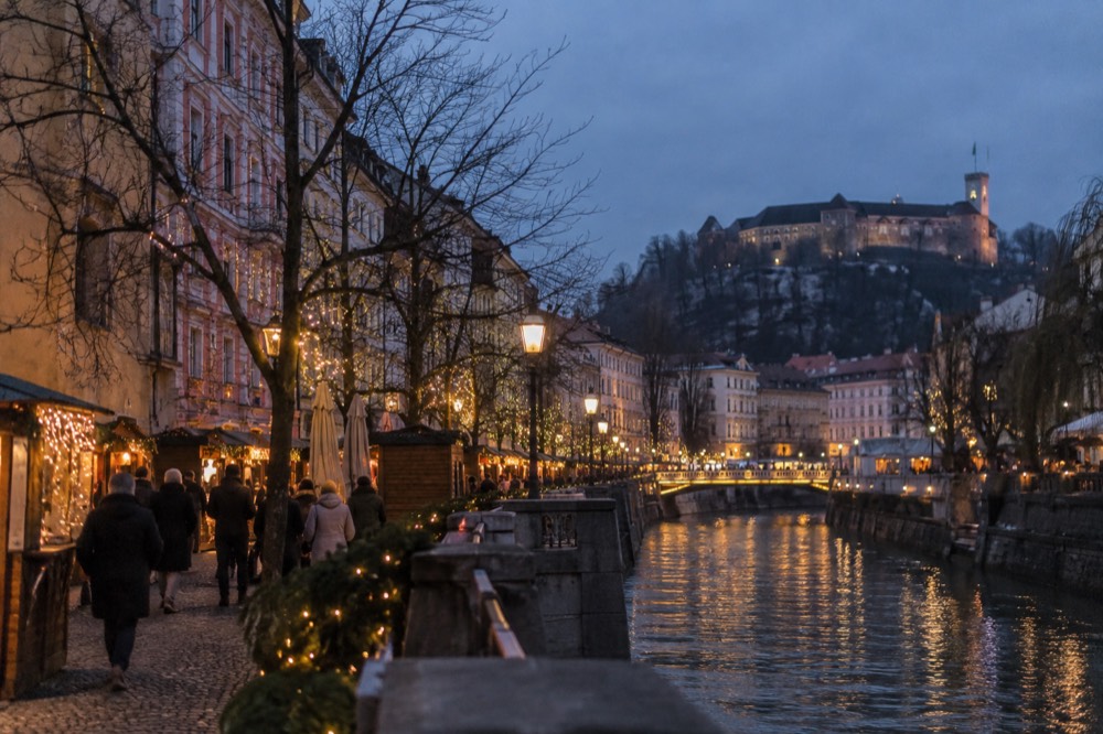 Christmas market stalls and festive lighting along the river embankment in the early evening
