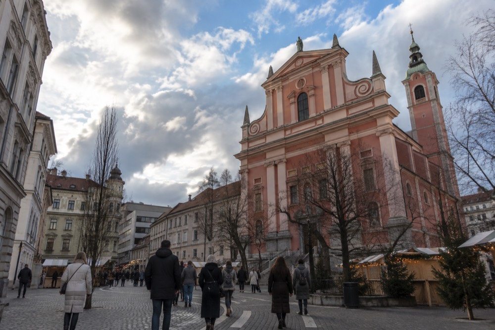 Winter coats and festive lights on a pedestrianised square in front of a church facade