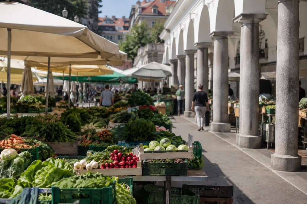 Market stalls with fresh produce under the arcades of Ljubljana's Central Market on a bright morning