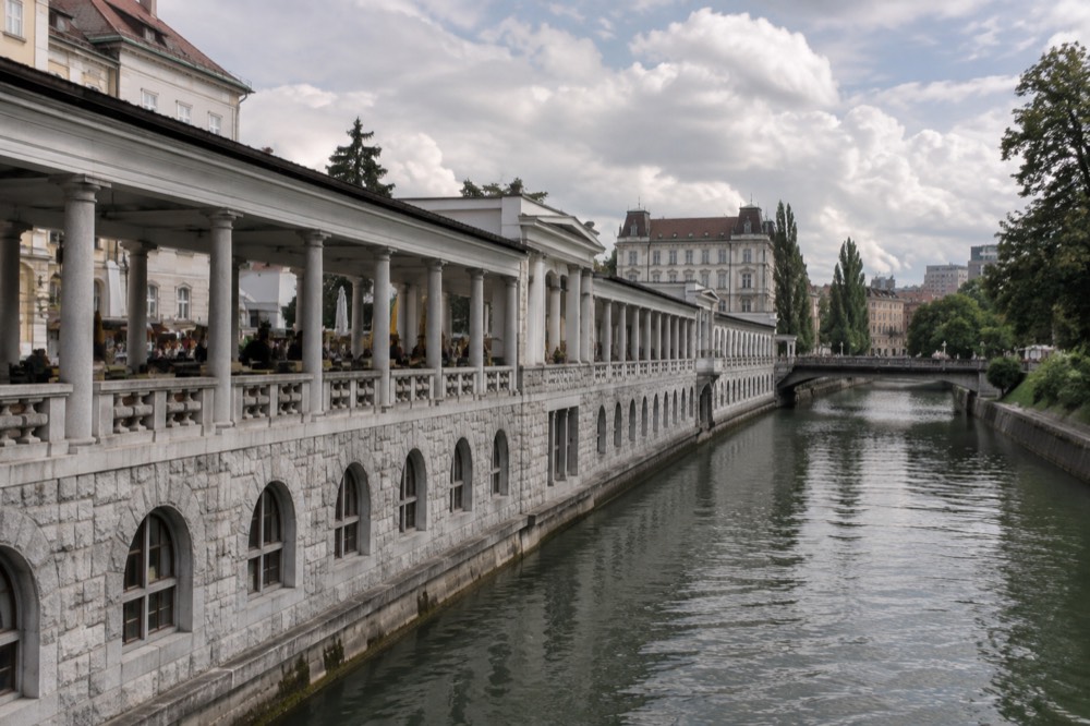 The stone colonnade of Plečnik's riverside market building along the Ljubljanica