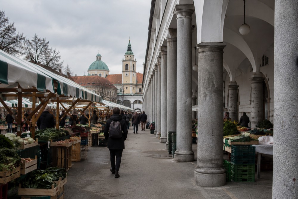 A visitor walking through market arcades towards the cathedral bell tower