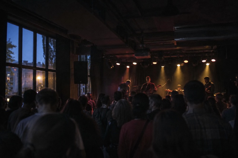 Small club interior with a live band on stage and a crowd in front
