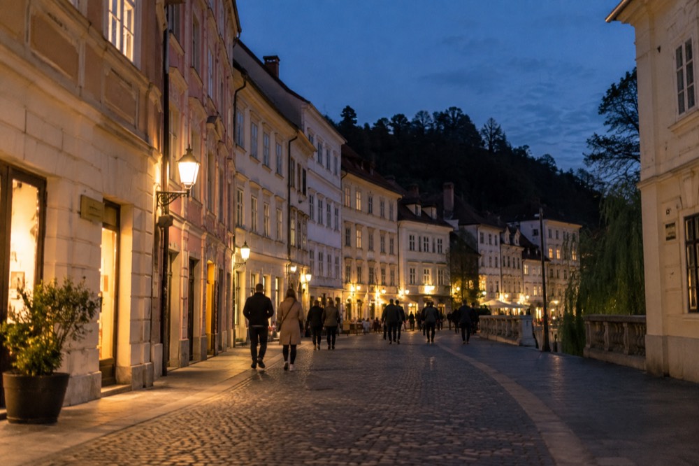 Lit pedestrian street in the old town at night with people walking