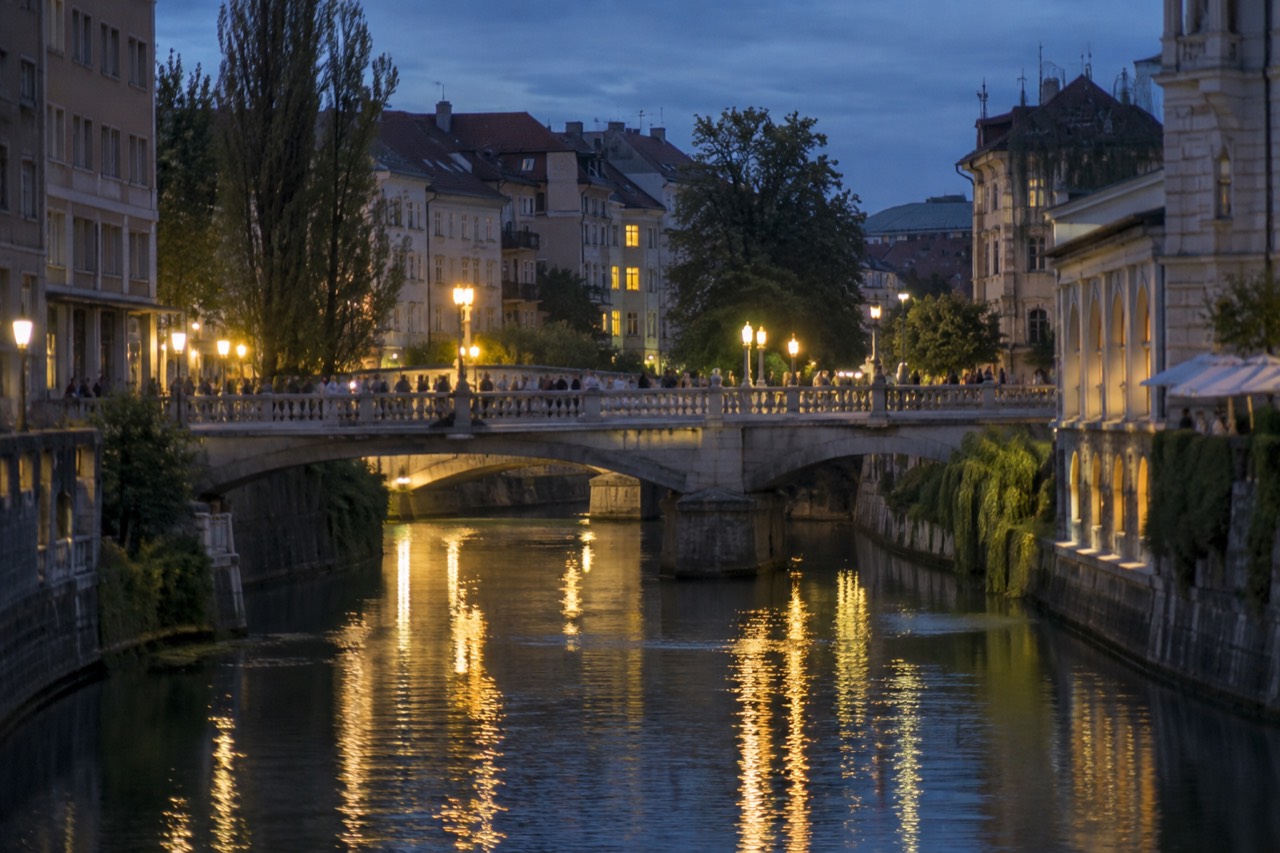 Evening lights reflecting on the Ljubljanica river with the Triple Bridge and old town buildings