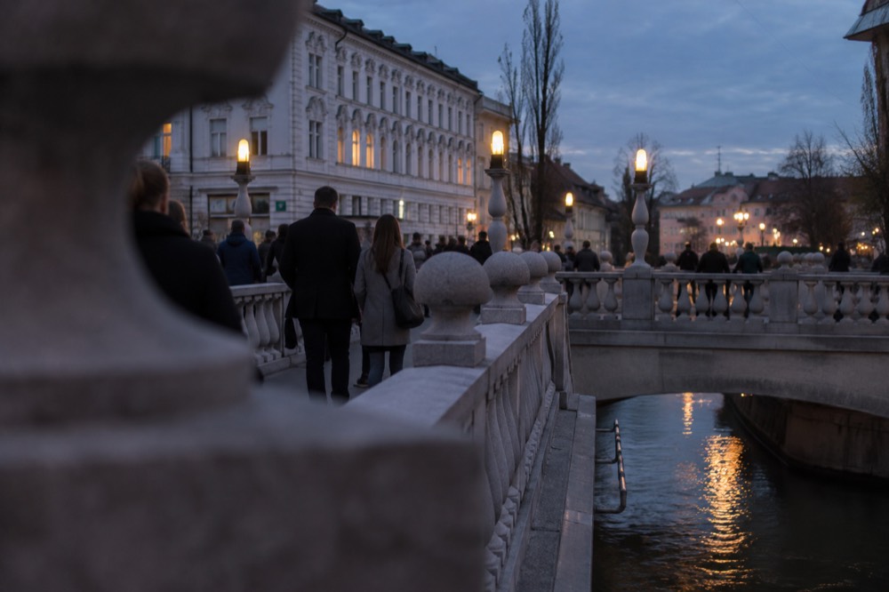 Visitors walking across the Triple Bridge in central Ljubljana