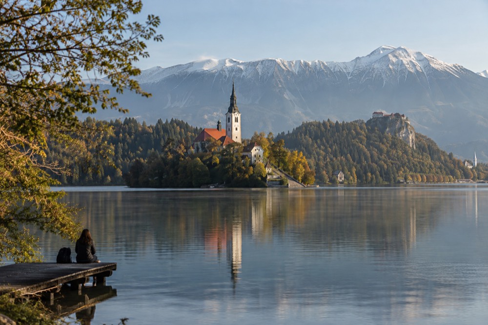 Lake Bled with the island church and forested shore in calm morning light