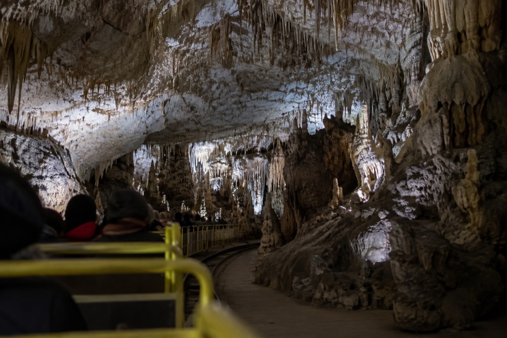 The cave railway inside Postojna Cave with visitors in the illuminated gallery