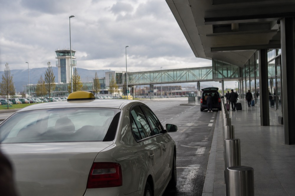 A taxi waiting outside Ljubljana Airport terminal on an overcast morning