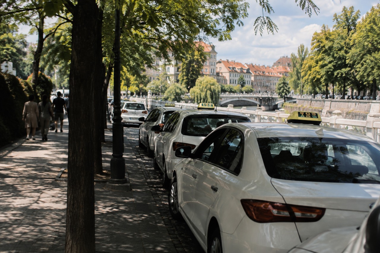 A taxi rank on a tree-lined street beside the Ljubljanica river in central Ljubljana
