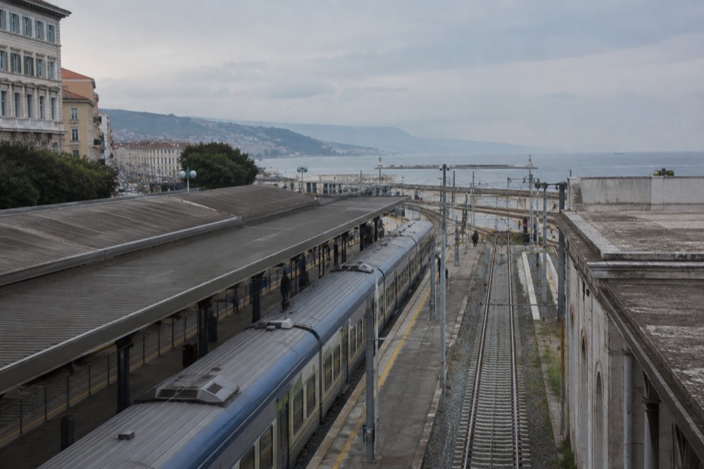 A railway platform with a regional train waiting under a grey sky