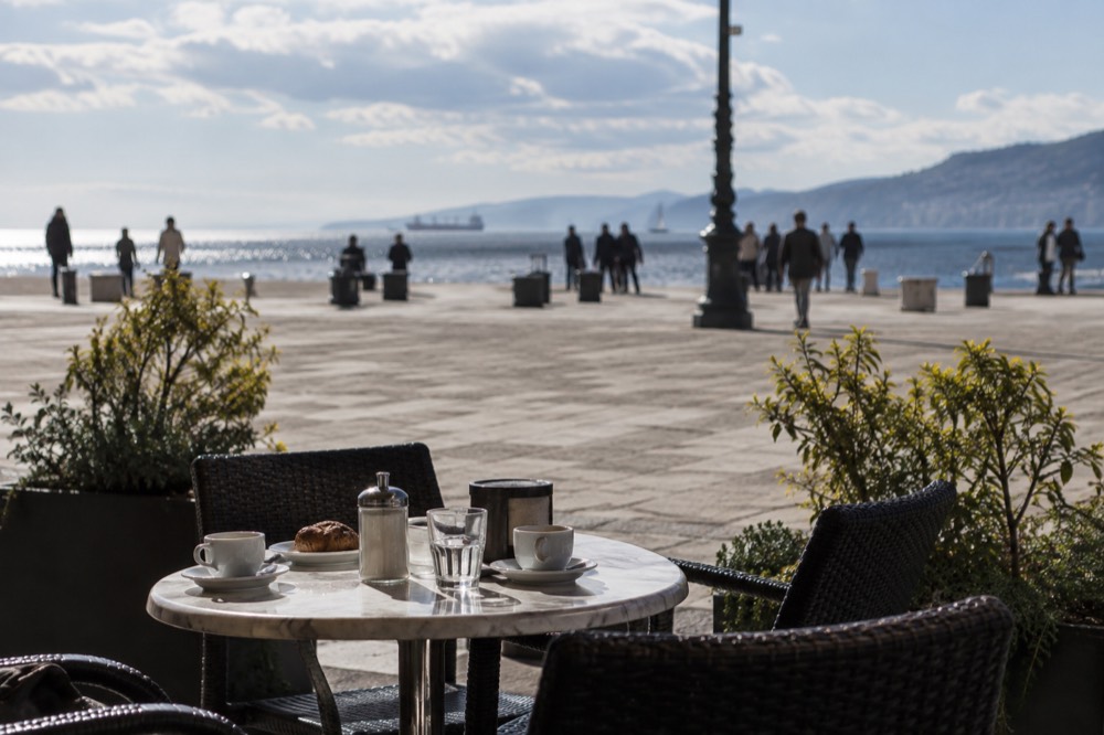An outdoor cafe table with coffee cups on a sunlit square