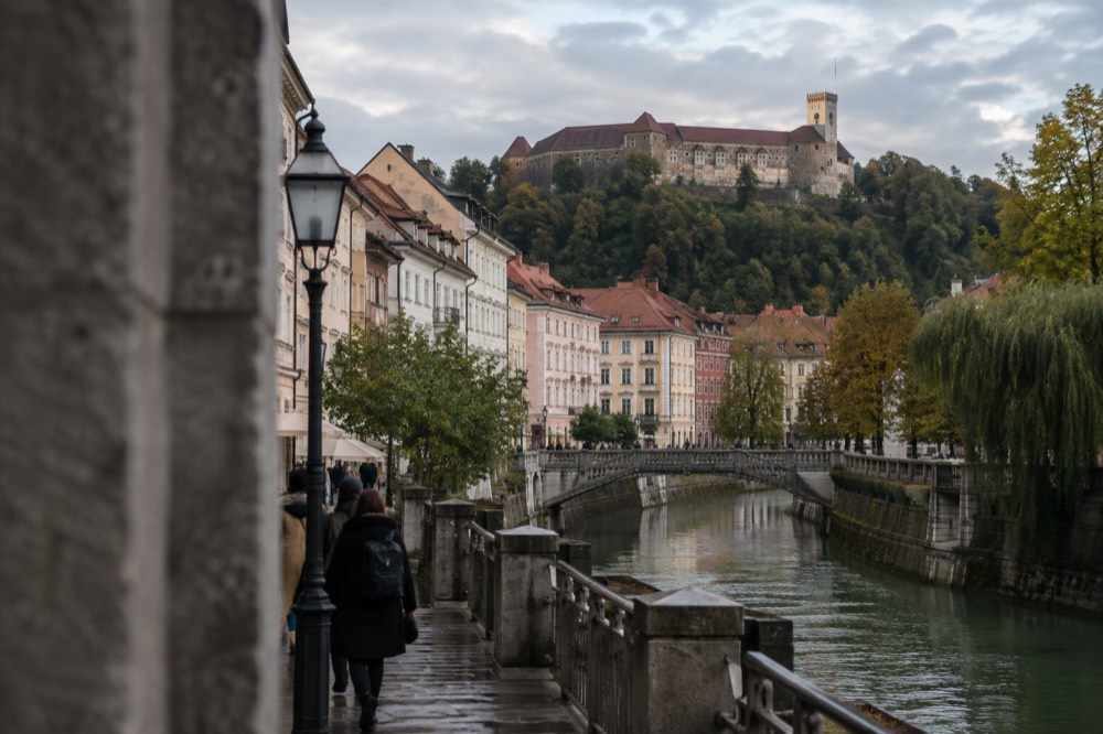 A hilltop castle above red rooftops and a river in a Styrian old town