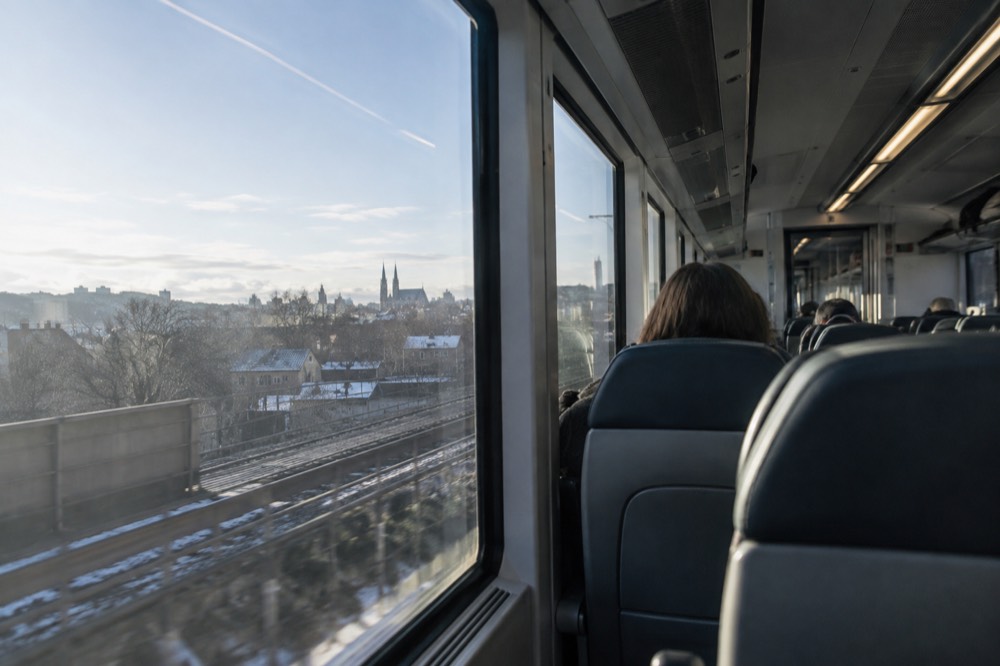 Interior of a modern rail carriage with passengers seated by large windows