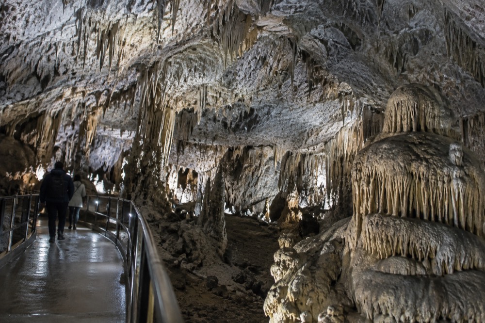Illuminated limestone formations inside a large show cave with a walkway