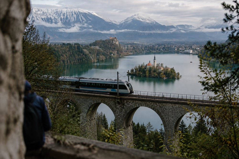 A train crossing the viaduct above Lake Bled with the island church below