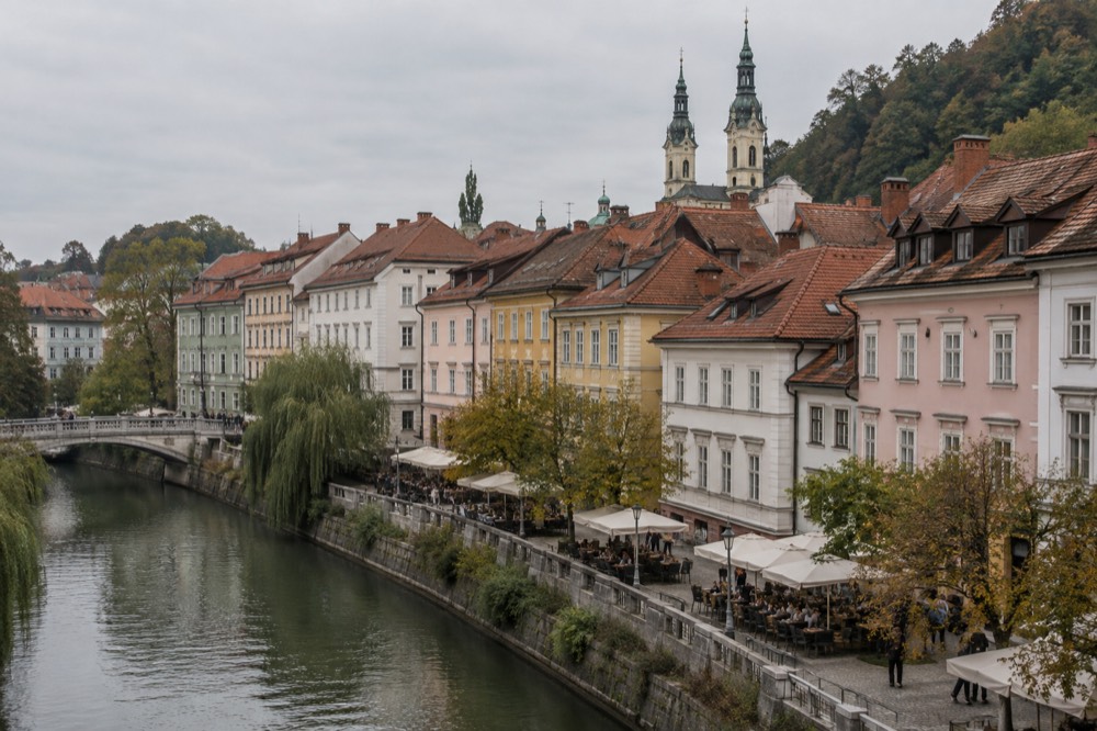 Café tables on a cobbled square with church spires behind them in Zagreb