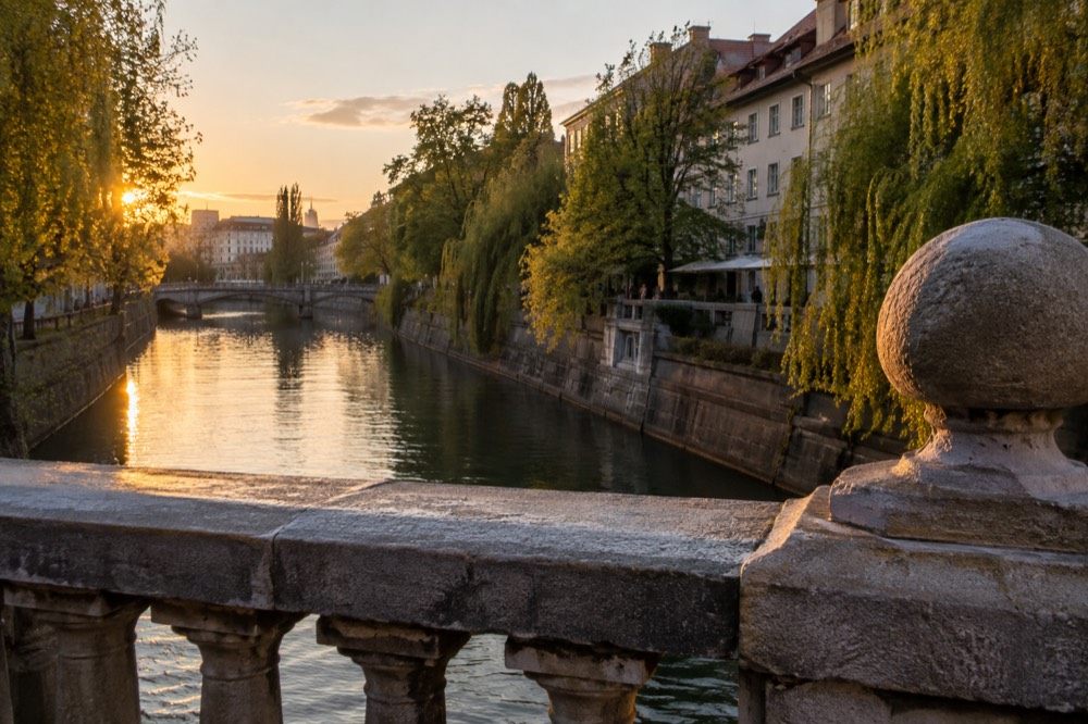 Stone bridge and riverside trees along the Ljubljanica at golden hour