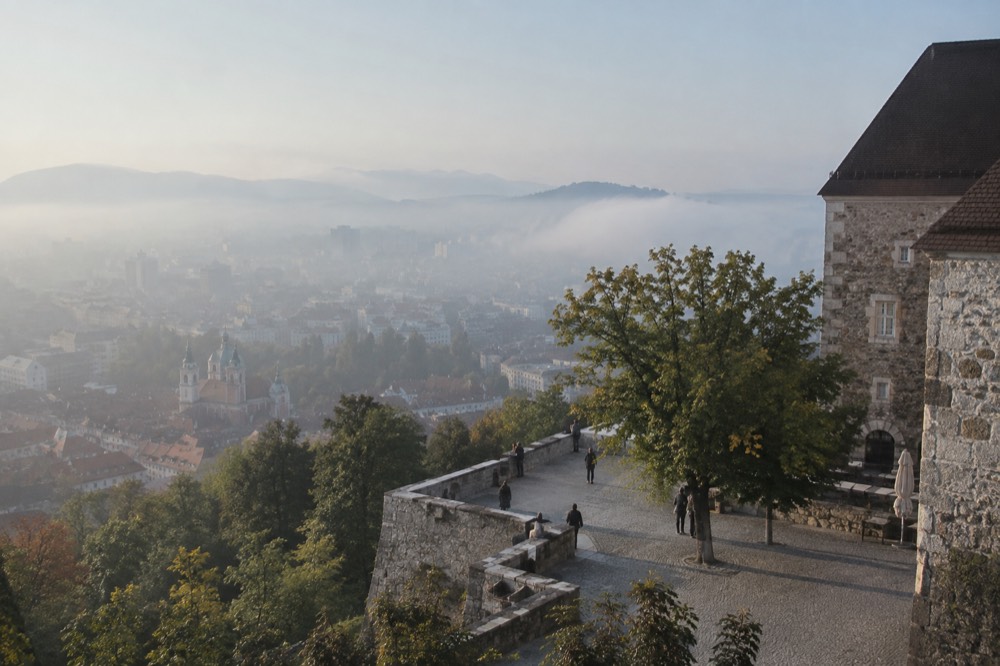 Morning fog low over the Ljubljana city rooftops with the castle hill above it