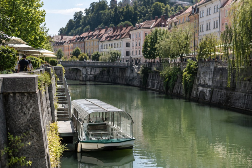 River pier in Ljubljana with a small electric boat moored beside a stone embankment