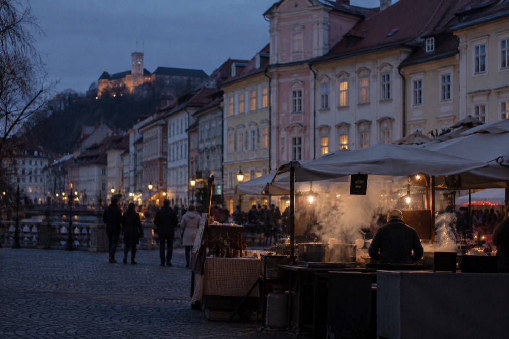 Open-air cooking stall with steam rising at dusk on a market square